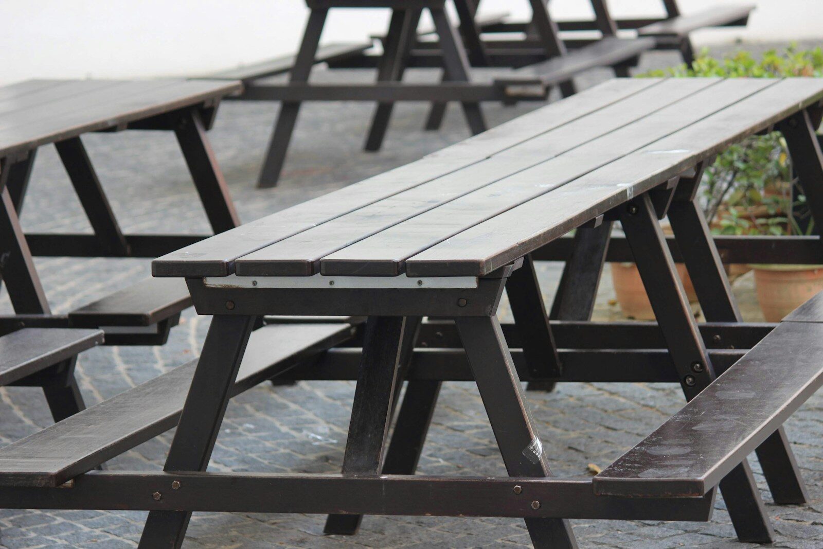 Several empty wooden picnic tables outdoors